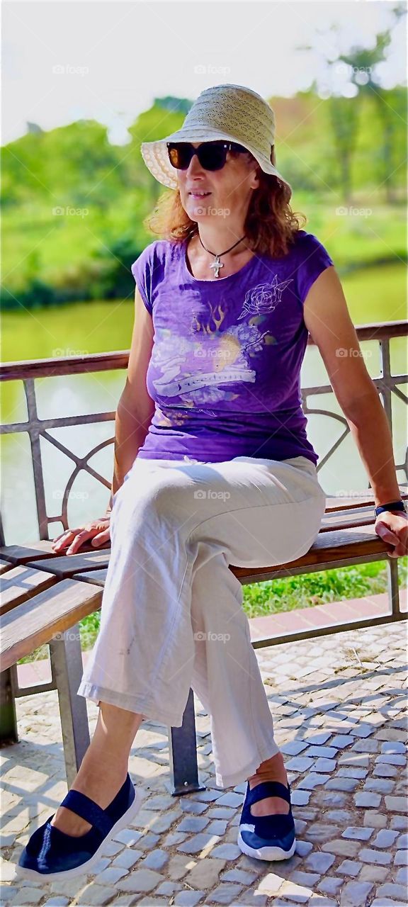 Sitting down on a bench outside at the botanical garden of “Berlin”, the now again capitol of Germany in the “Steglitz” district our lady is relaxing and taking in the beautiful sights by the water. 2024. Hypnotic Productions