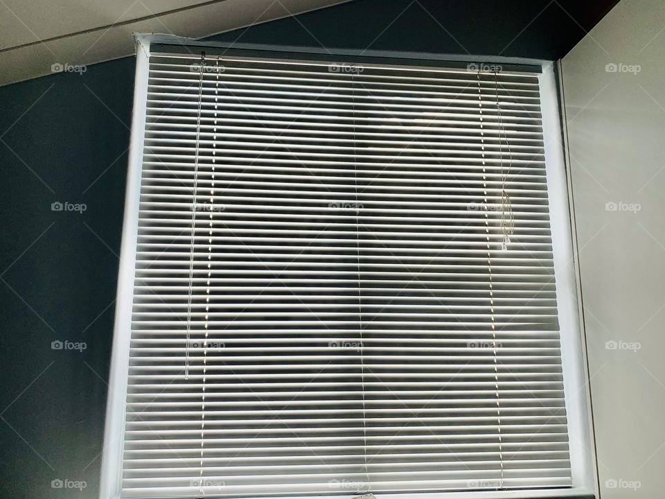 Closed blinds at a window in a bed.