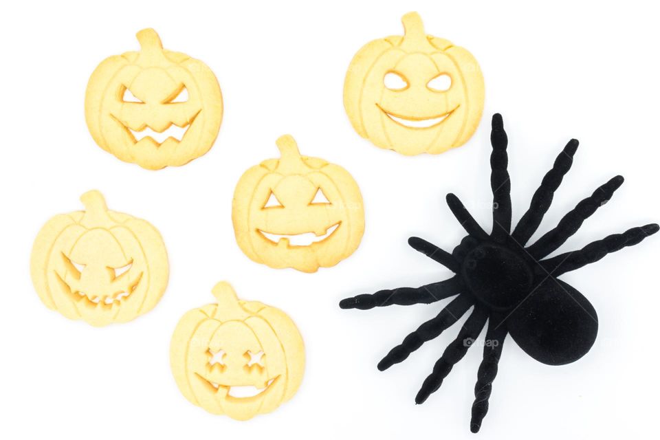 Halloween pumpkin-shaped cookies with a toy black spider.