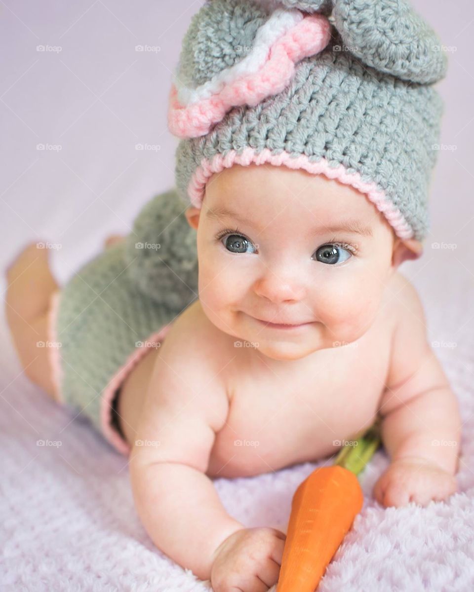 A Baby With A Carrot In A Bunny Costume