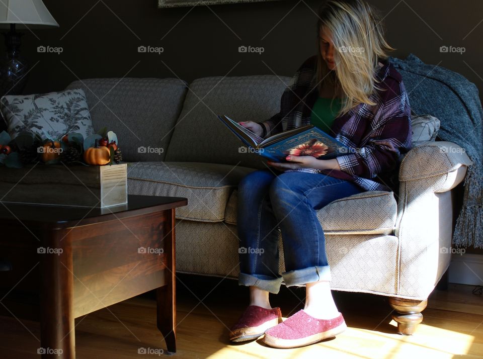 Keeping Sharp; Woman ready a book on a couch with light coming in through window