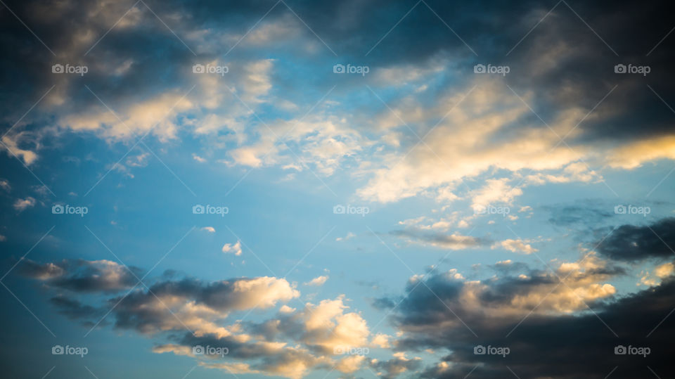 Large clouds float across the sunset sky like sails.