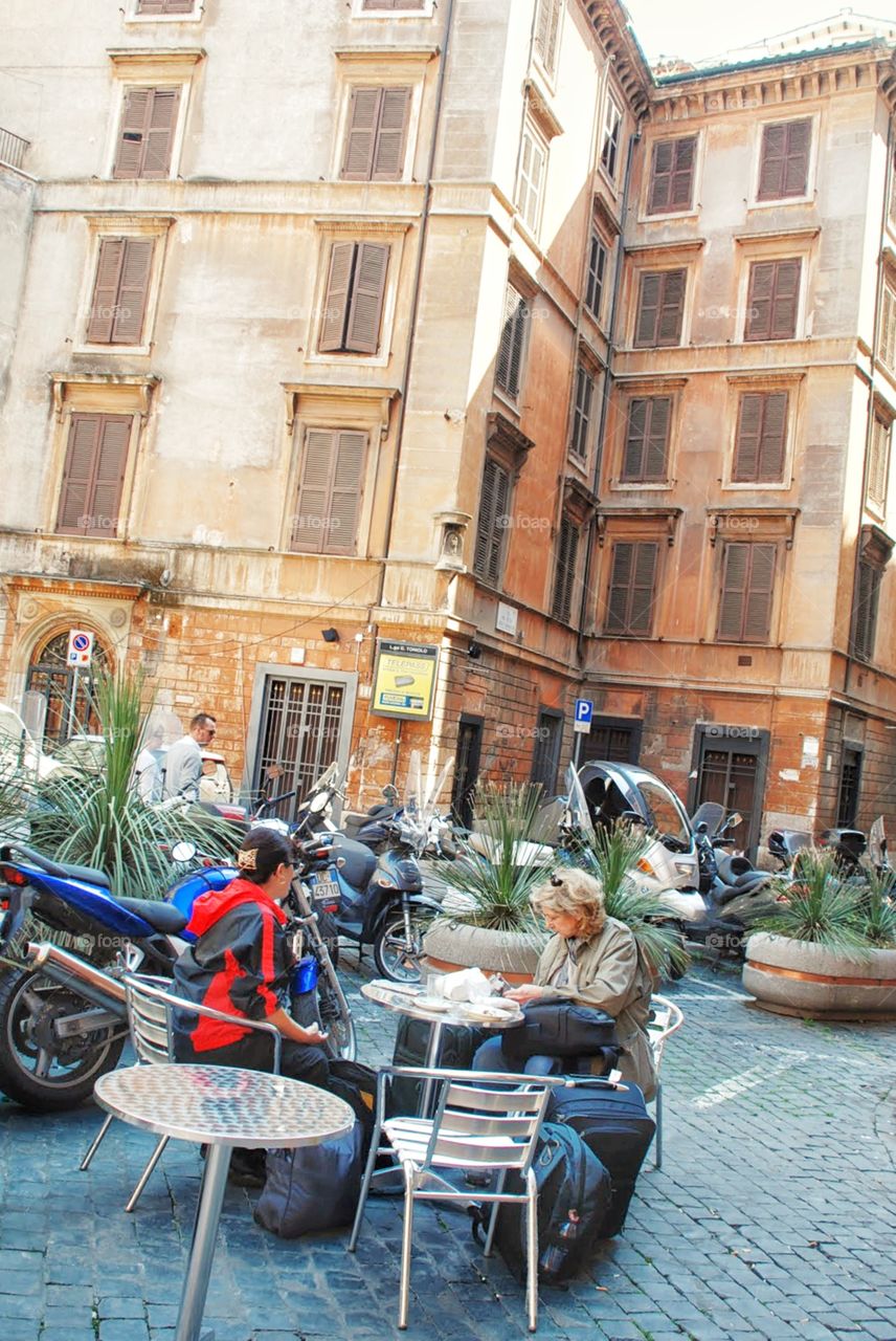 Making plans . Two women sit at an outdoor cafe making plans for a day in Rome