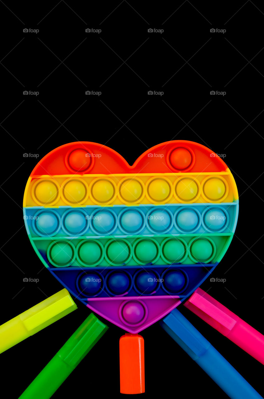 Top view of anti stress sensory toy Pop it rainbow heart on white background. Popular, trend toys in 2021