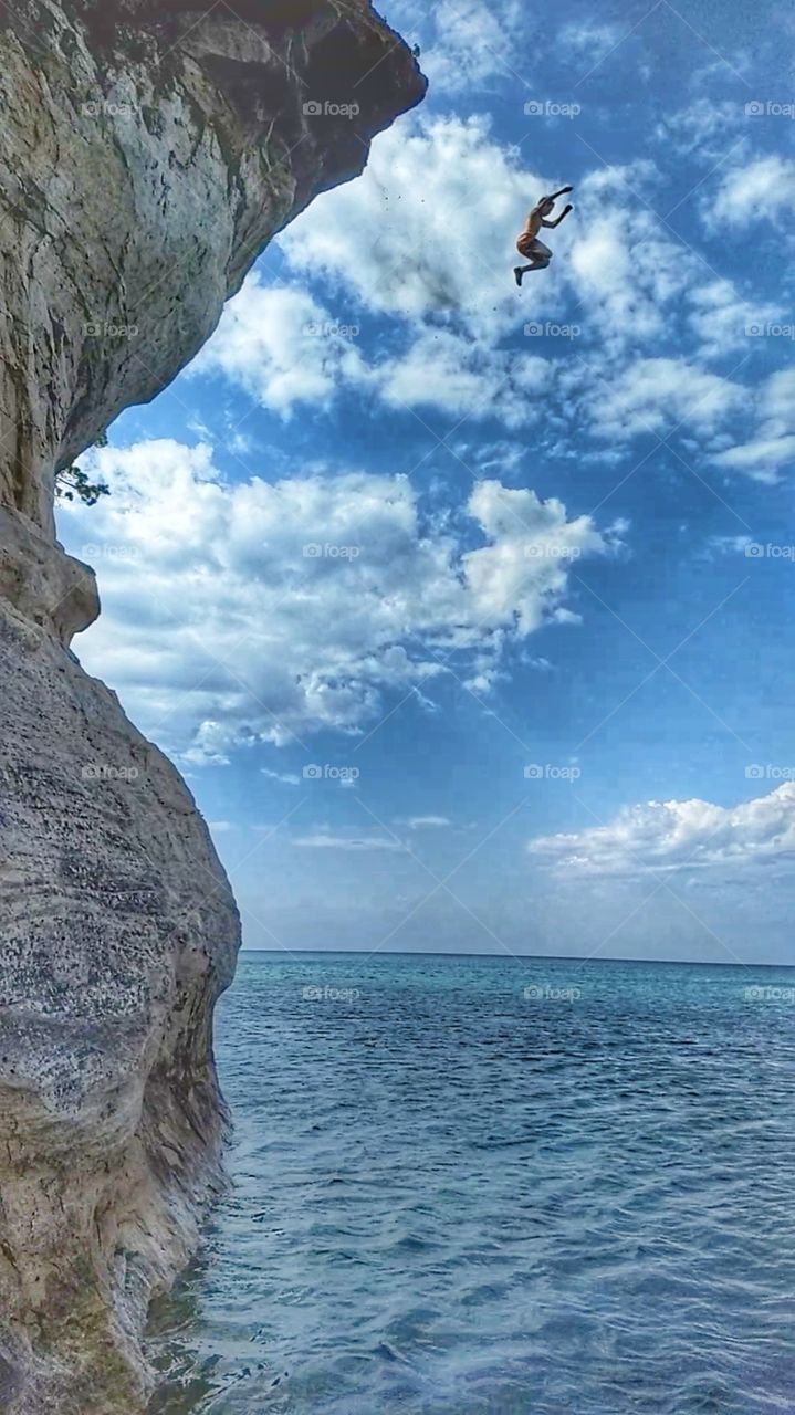 Cliff diver in midair over Lake superior