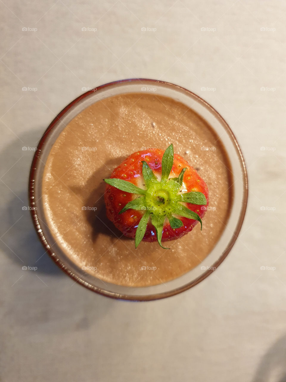 A portrait of a glass filled with chocolate mousse with a strawberry on top. Sweet and a finish of fruit is always great.