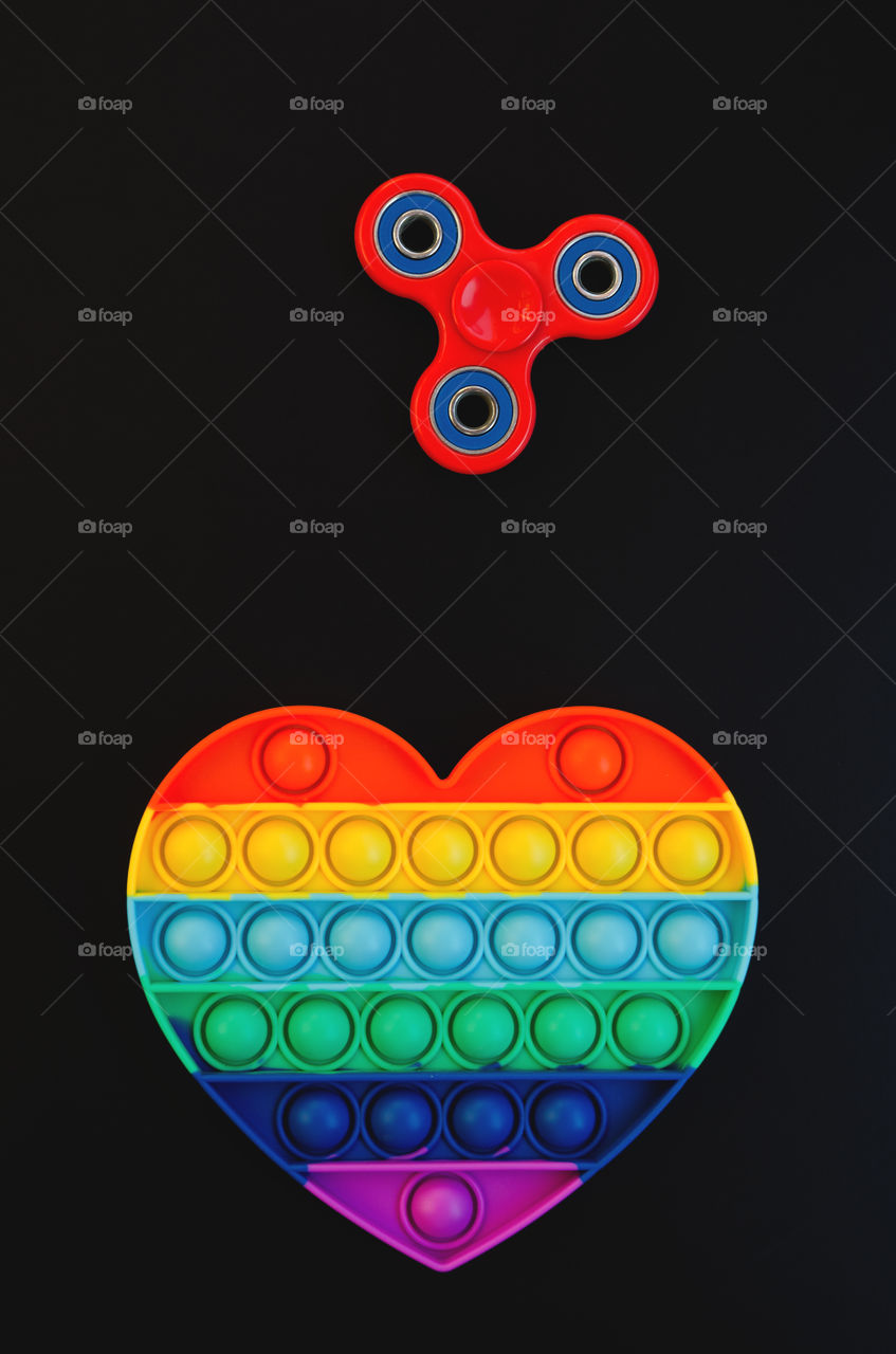 Top view of anti stress sensory toy Pop it rainbow heart on white background. Popular, trend toys in 2021.