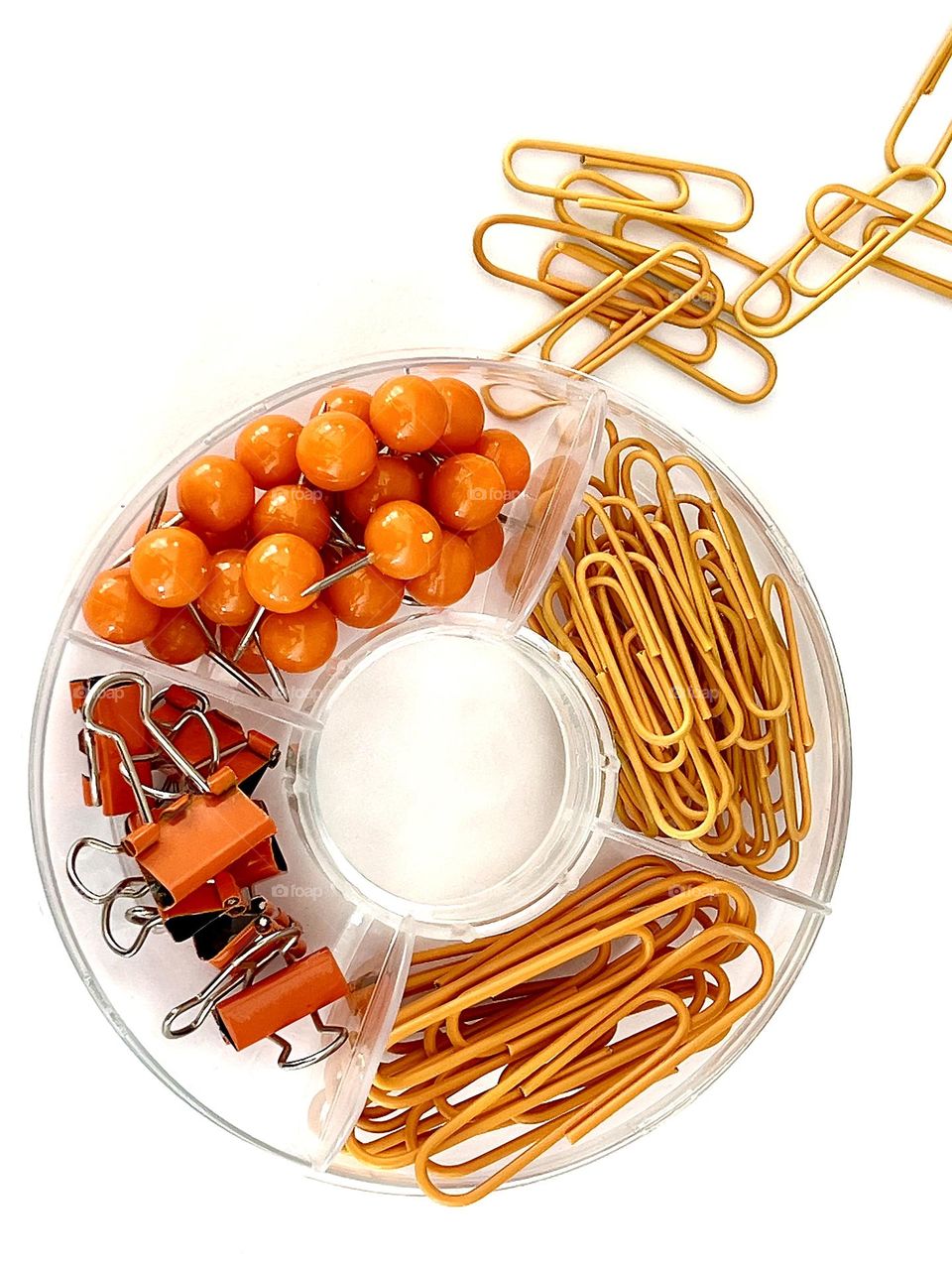 Stationery. Bright orange paper clips, paper clips, push pins in a round box. 