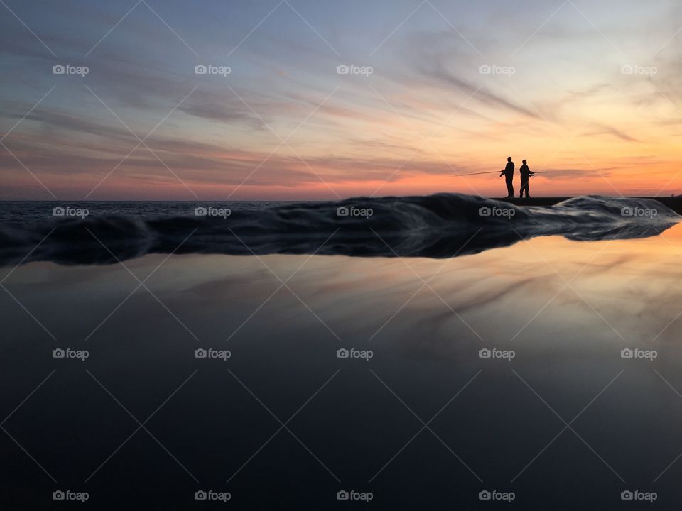 Two fishermen fishing on the sea. 