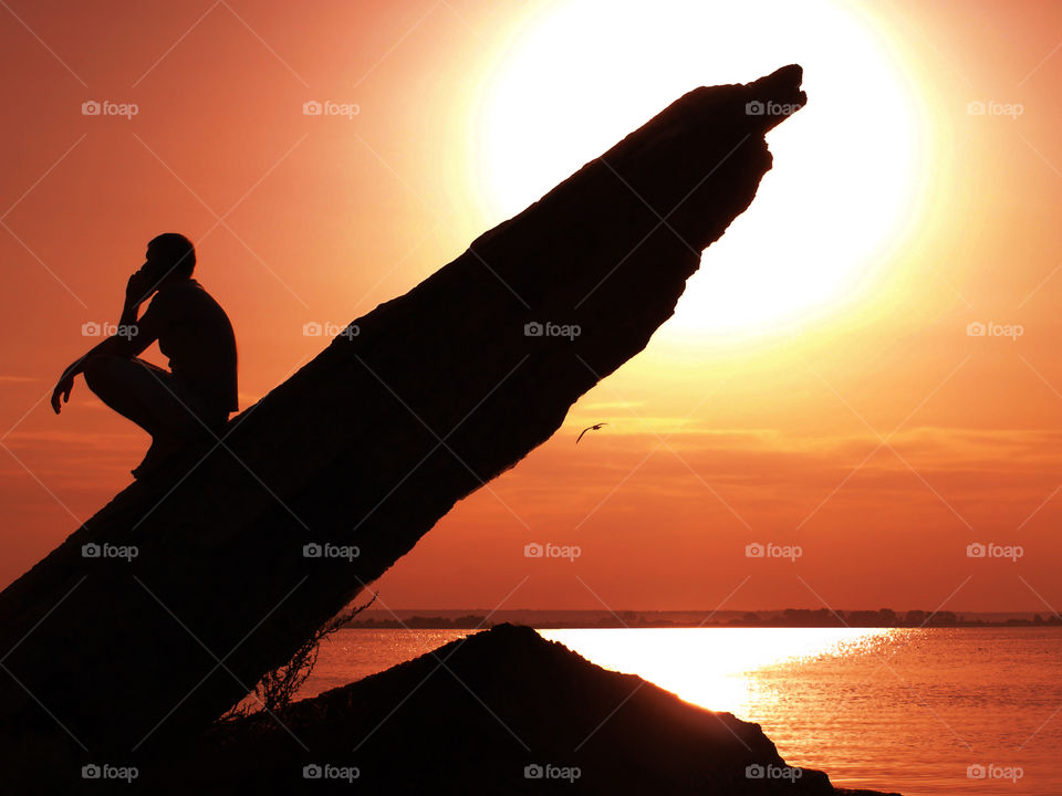 Men silhouette on the rocks, sunset background