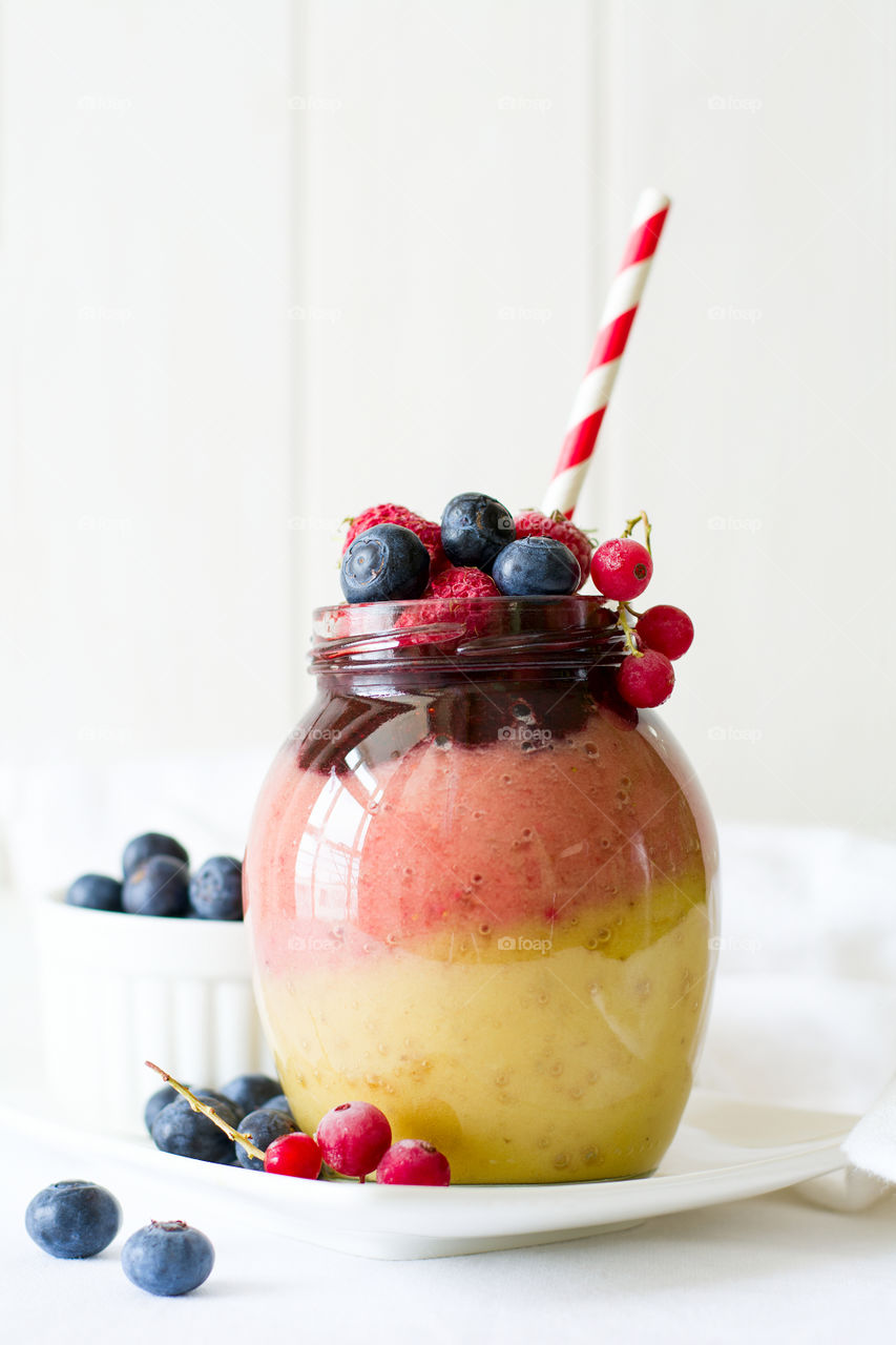 Colorful smoothie with banana, strawberry, raspberry and blueberry in jar