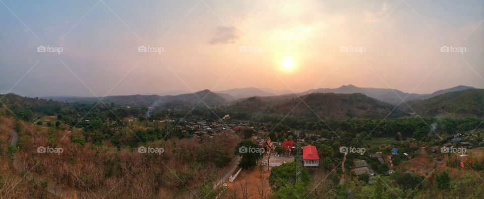 Beautiful panoramic aerial view of the rural village farming area on the mountain with sunset sky in the background. San Pa Tong District, Chiang Mai, Northern Thailand.