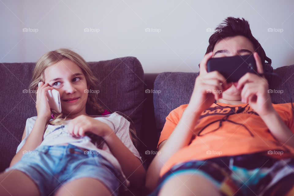Brother and sister using mobile phone
