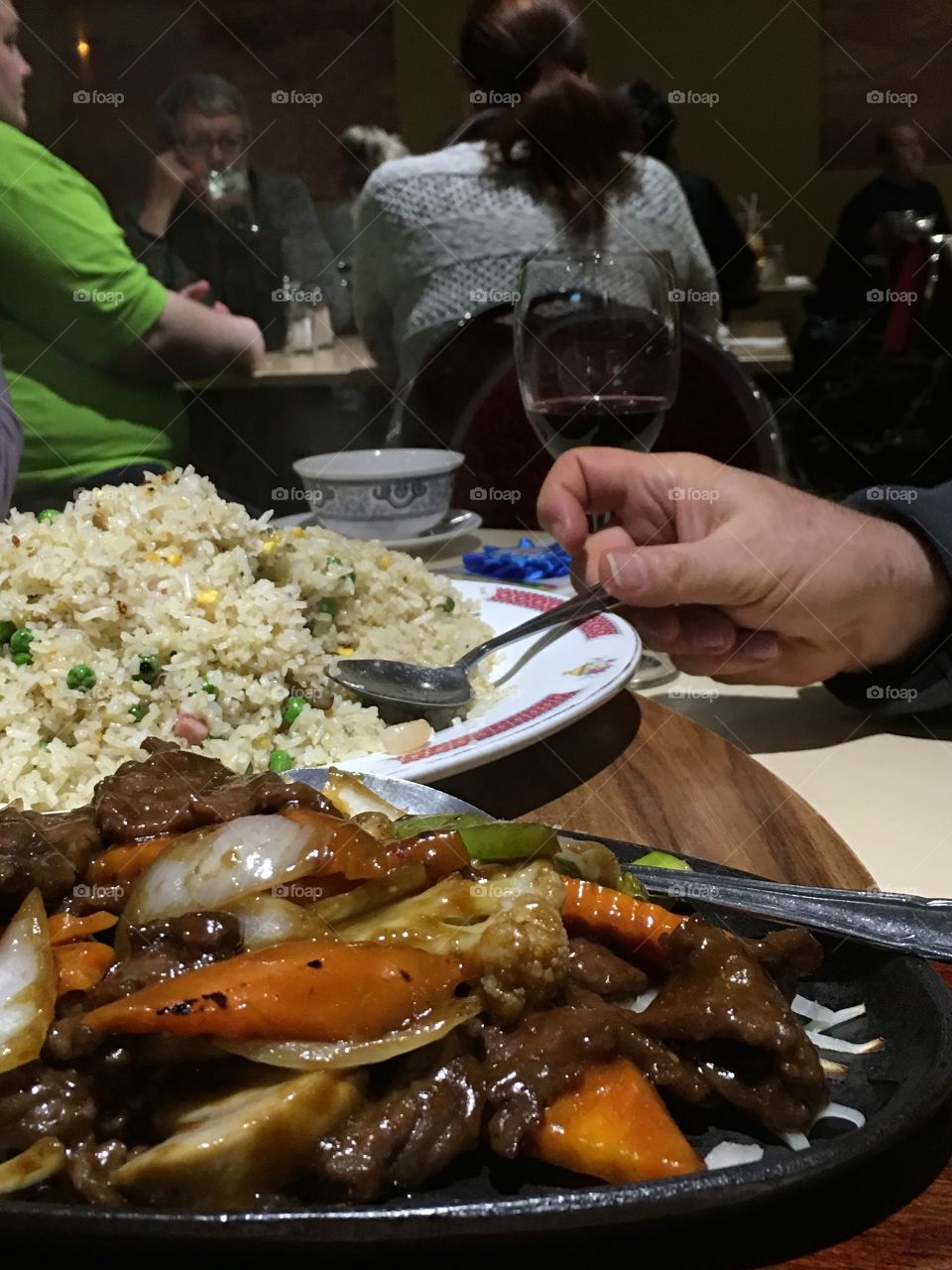 Hand in picture servicing Chinese shrimp fried rice on plate 