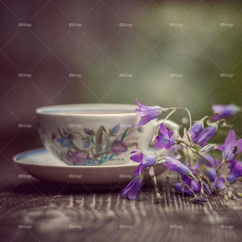 Vintage cup if herbal tea and bouquet of bell flowers 