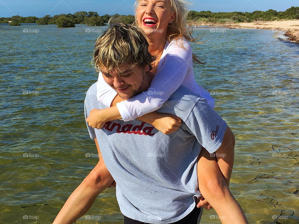 Attractive young couple piggybacking at lake