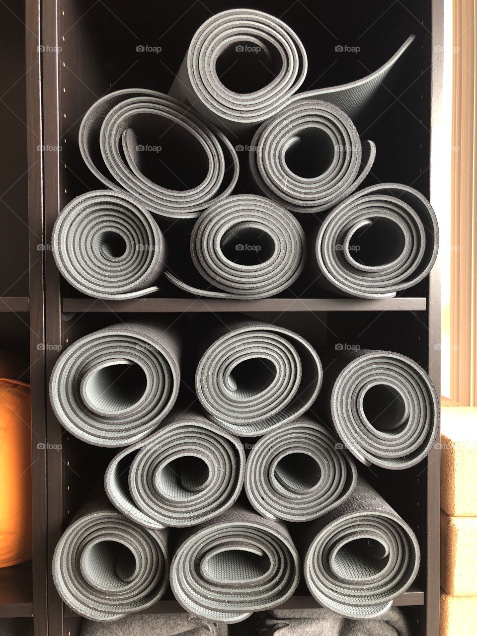 Grey yoga mats in a black cupboard ready for the yoga class