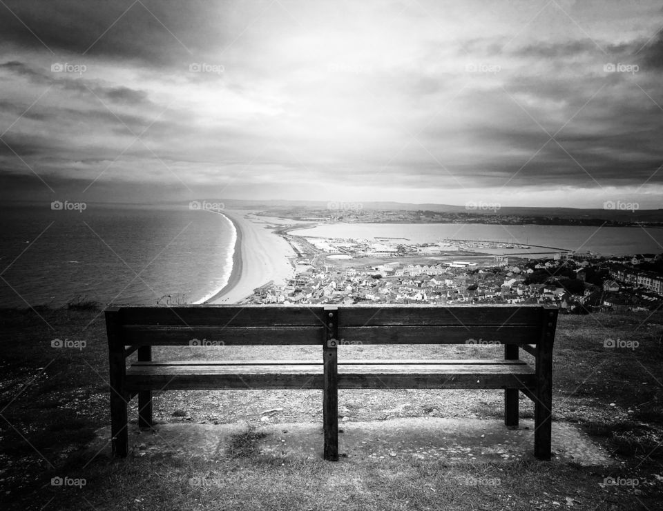 Ray of light hitting empty park bench overlooking Weymouth harbour. 