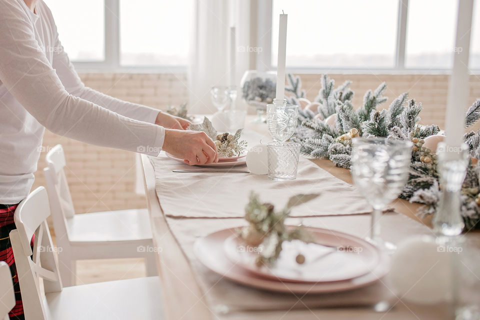 man sets a beautiful decorated winter table for a festive dinner.  Merry Christmas and Happy New Year.