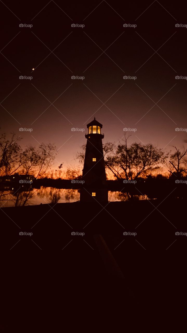 Lighthouse capturing the Ending of a Gorgeous Day. Backlit Glow lighting up the Entire Shoreline and Lakebed. 