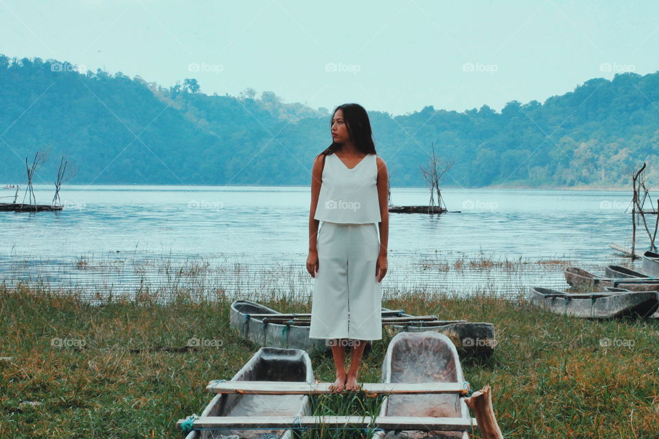 woman standing on the old fisherman boat at the lakeside