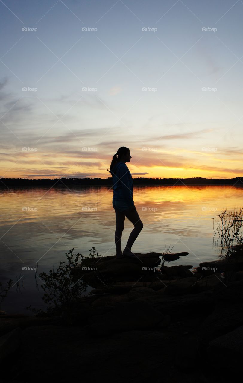 Silhouetted woman practicing yoga at sunset