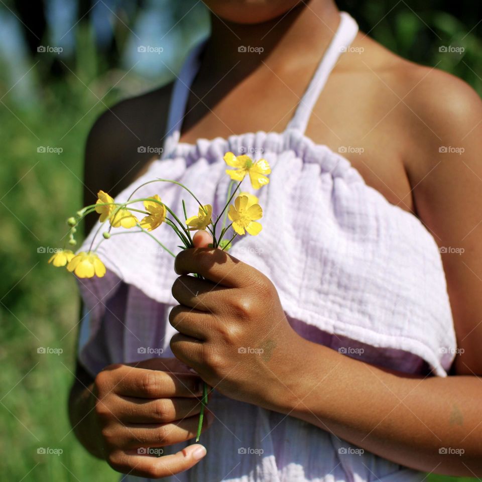 Girl of mixed race picking wildflowers in a barley field during summer time