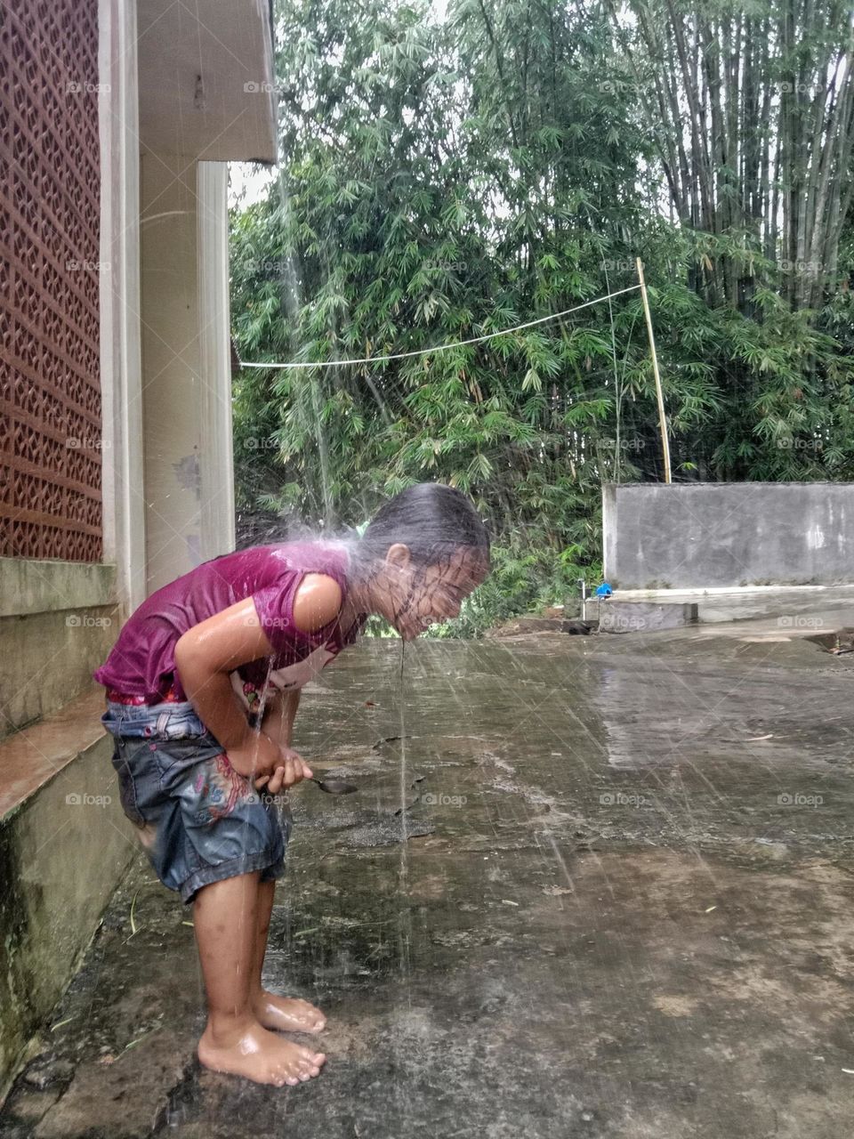 A little girl is playing in the rain.