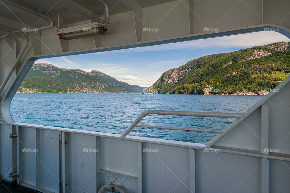 Ship deck window opening on fjord ferry with a view at strait and mountains.