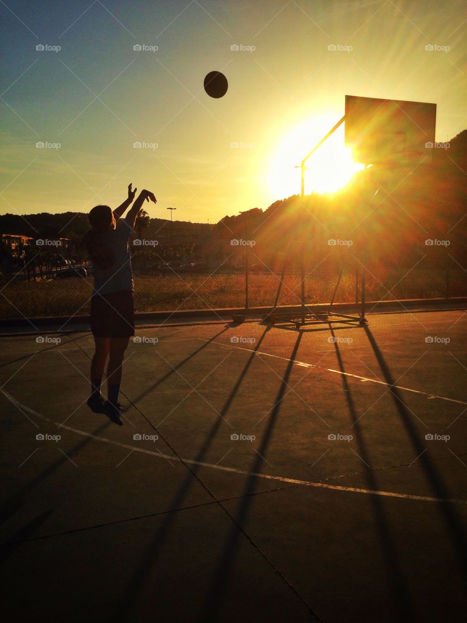 Basketball at the sunset. Triple shot, a ball & the setting sun