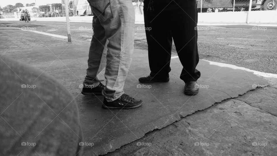 Pernas e pés de homens conversando.