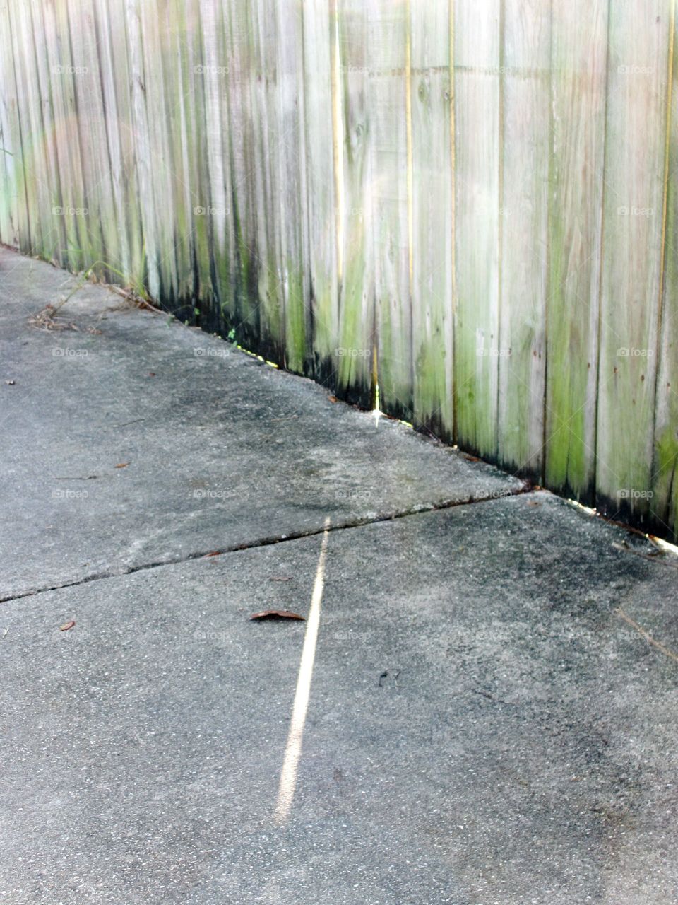 ray of sunshine. Ray of sunshine shining through wooden fence across sidewalk