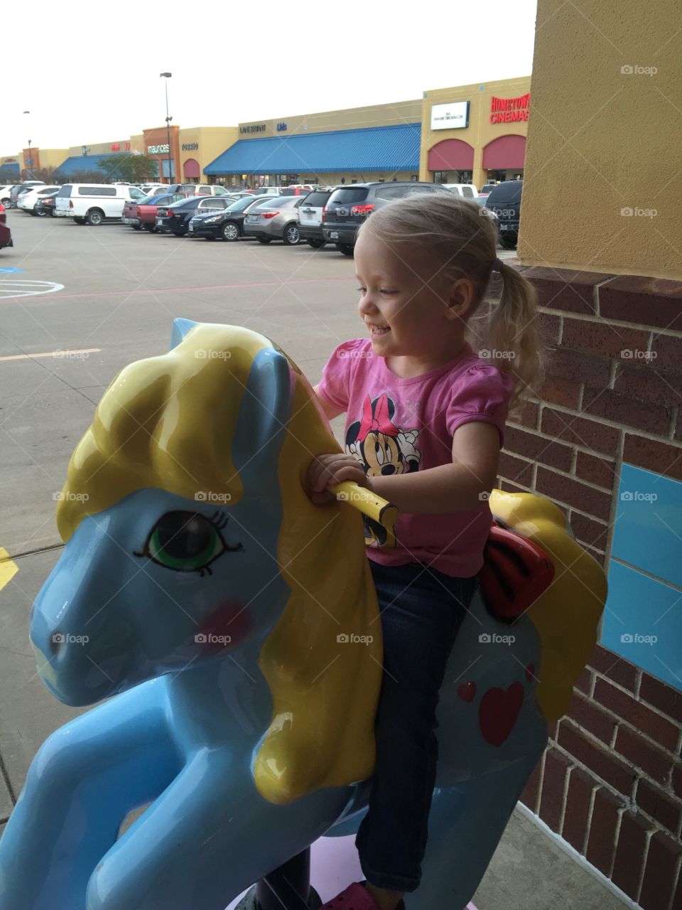 Toddler on pony ride. Girl enjoying a pony ride at the shopping mall