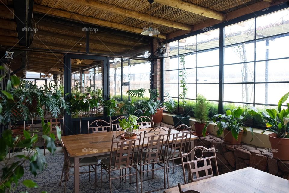 Cafe interior with wooden and metal , green plants and big windows