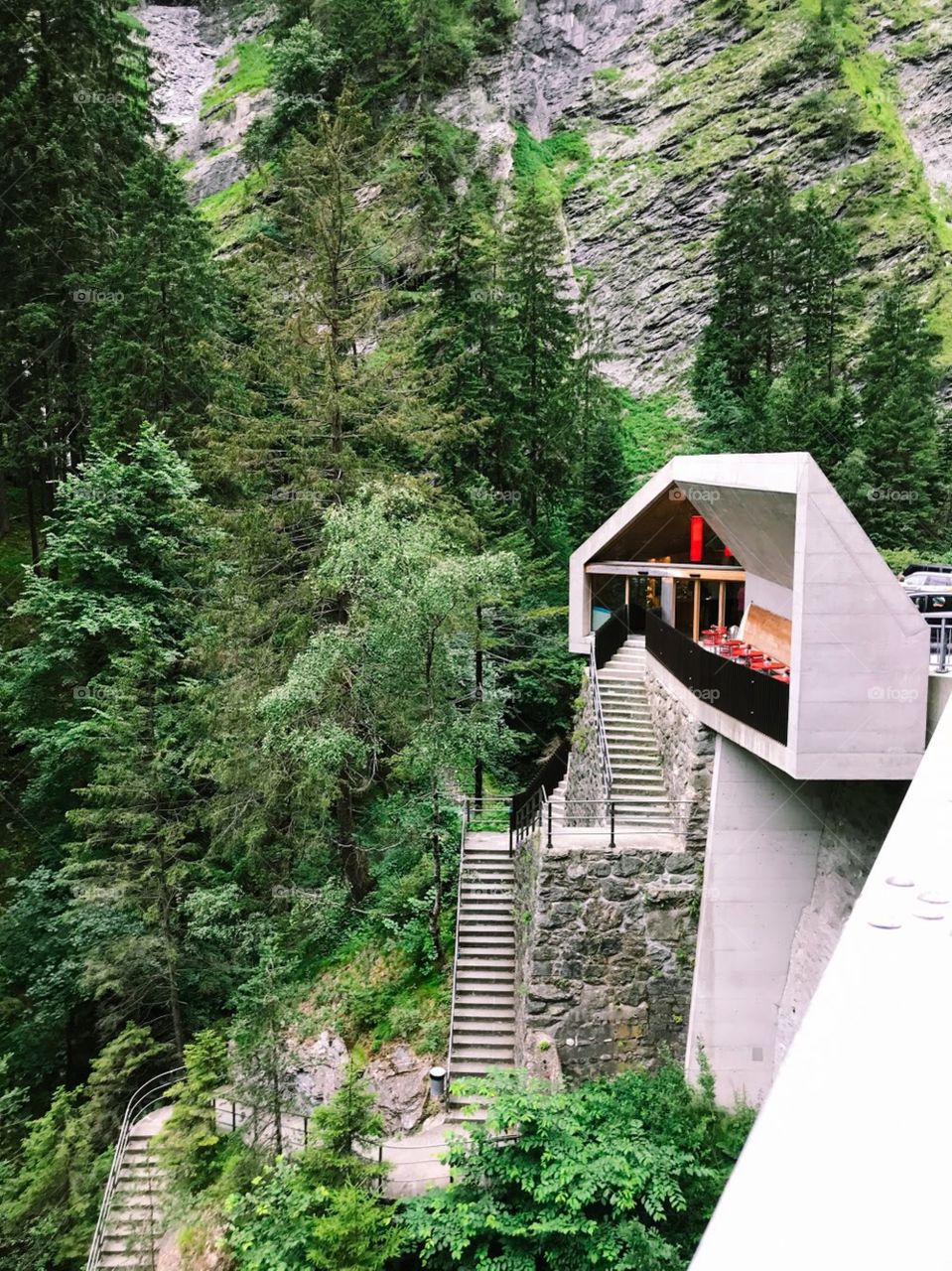 A stop in for sightseeing in a famous canyon in Switzerland.  The white place is to sell admission tickets , then there are many step to go down, besides there are many green trees and Cliff