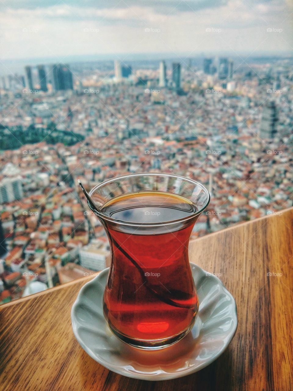 Scenic view to the big city life with a lot of houses and road against cup of tea at table.