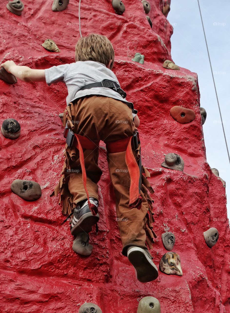 Young Boy Climbing A Rock Wall
