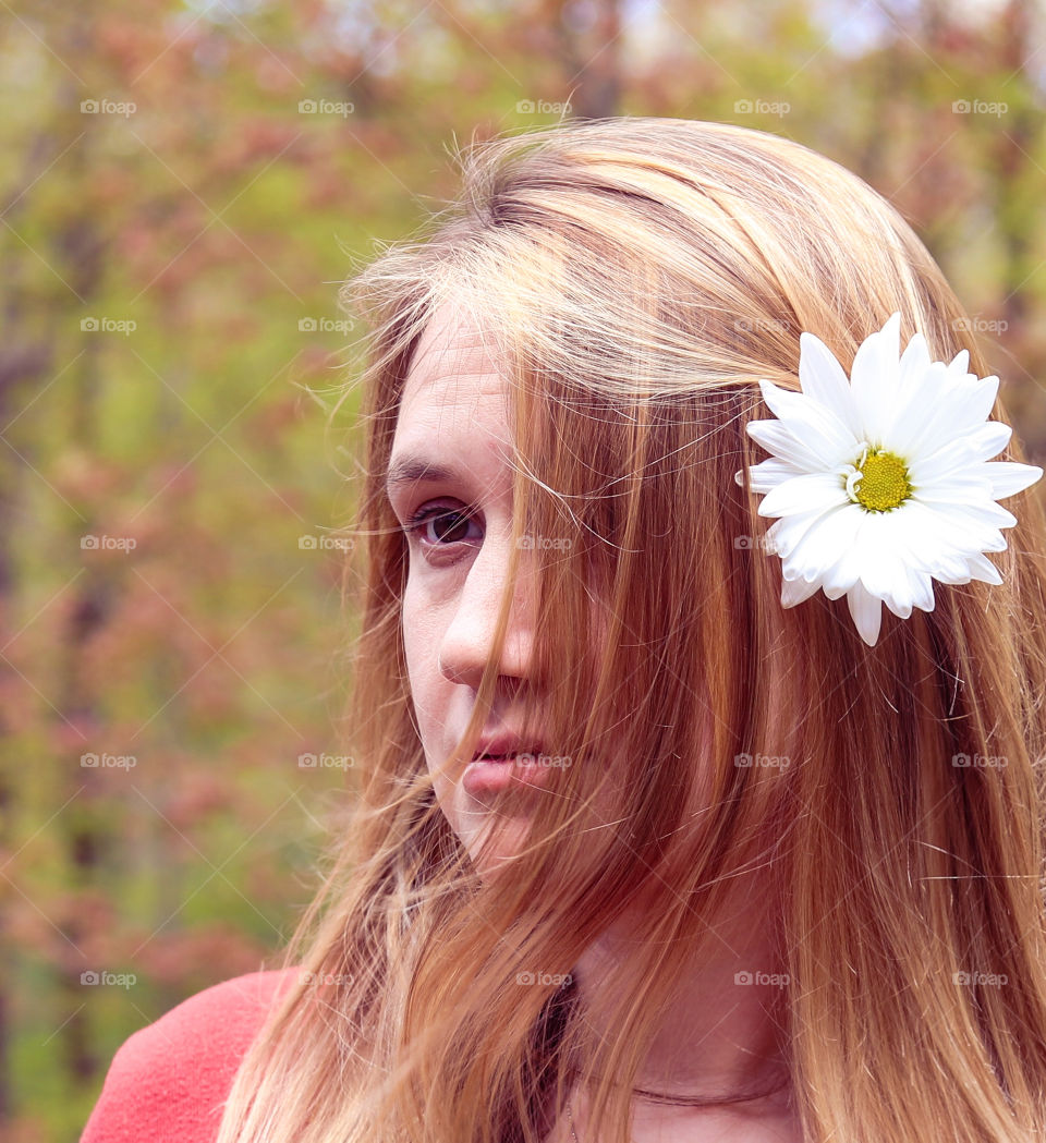 Pink Summer Evenings; Woman with White daisy in her hair wear a pink sweater, staring off with pinkish blossoms in the trees behind her. Warm-Pink overall tone 