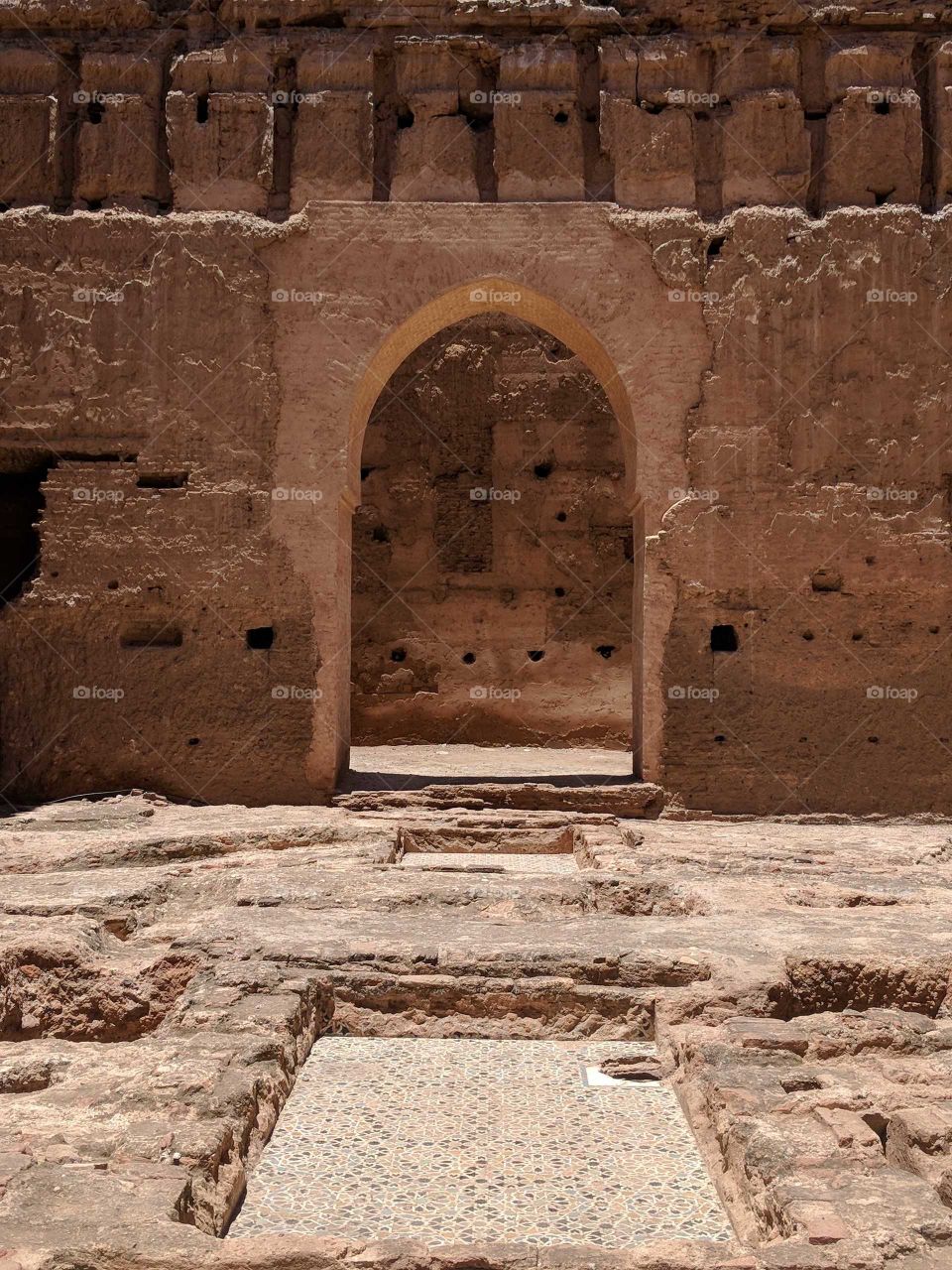 Exploring the Ancient Ruins of the Palais El Badi in Marrakech in Morocco - Brown Stone and Clay Arch in the Wall and Ceramic Tile Mosaic Floors