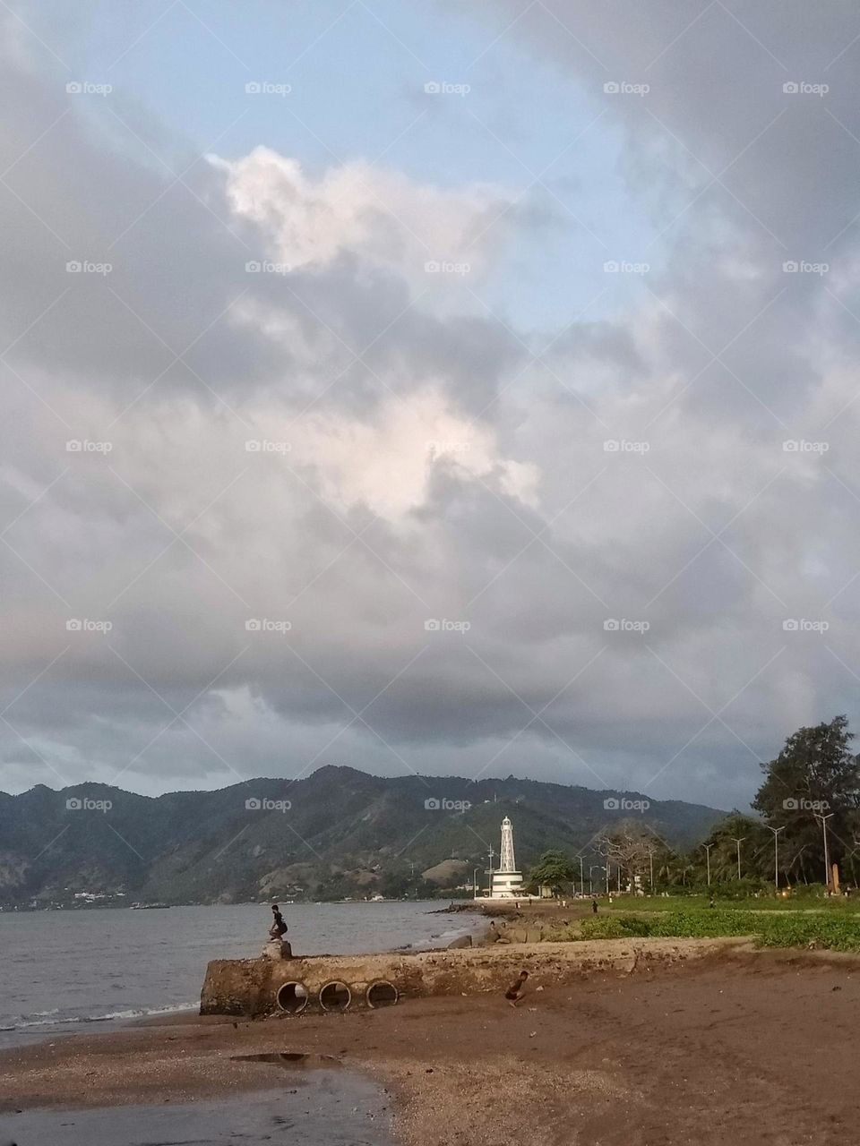 Díli lighthouse, Farol on a cloudy afternoon, people exercising