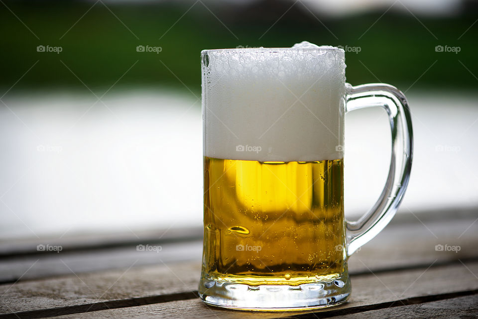 Glass of splashing beer on wooden table