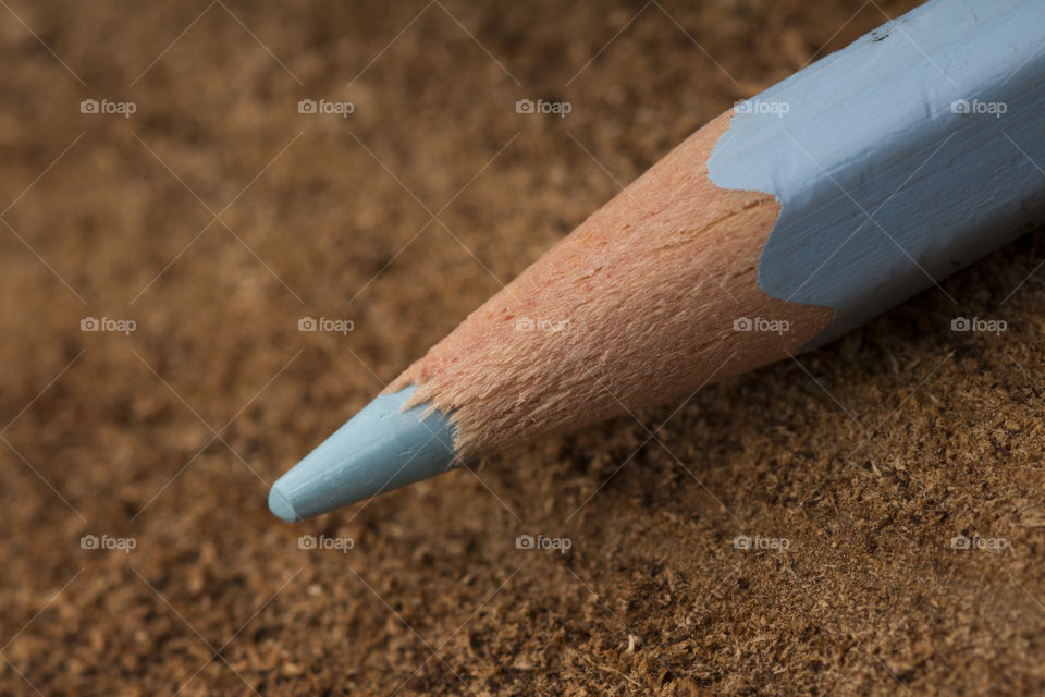 close up photo of the tip of blue pencil on a dark wood background.  macro shot