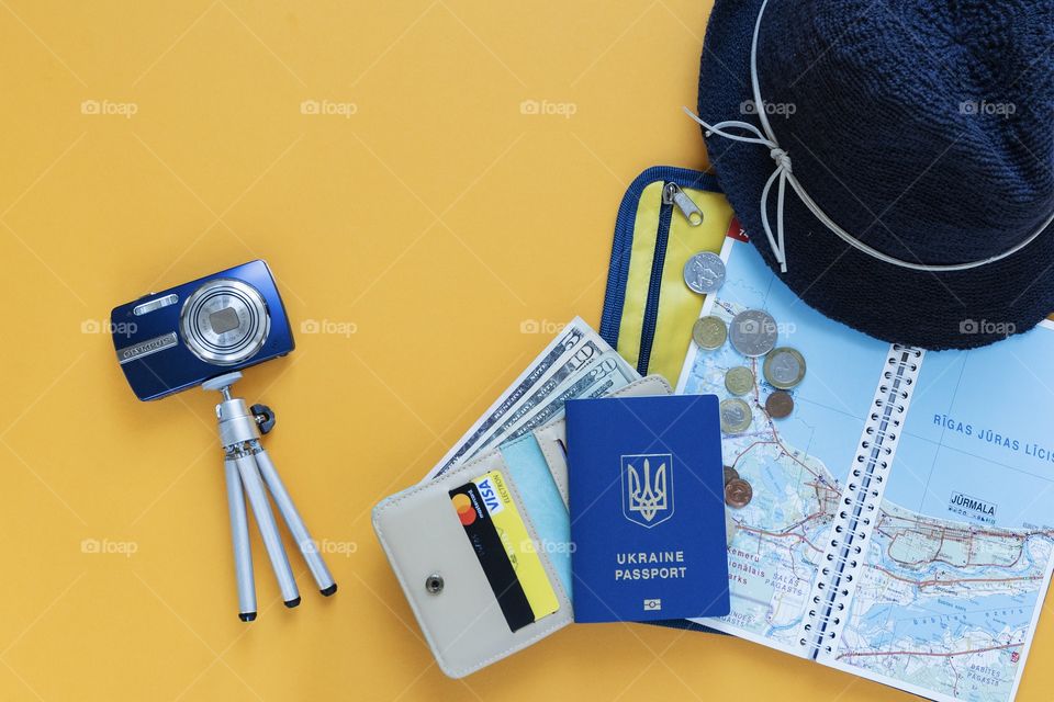 on a yellow background things to travel, passport, wallet, camera, money, debit cards, hat