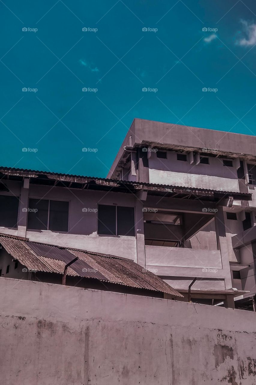 Multi-storey building in the photo from below. Building. Multi-storey building. Window. Wall. Critical. The sky. Blue sky. Clouds. Gray gray. Photography. Aesthetic. Minimalist photography. Scenes.