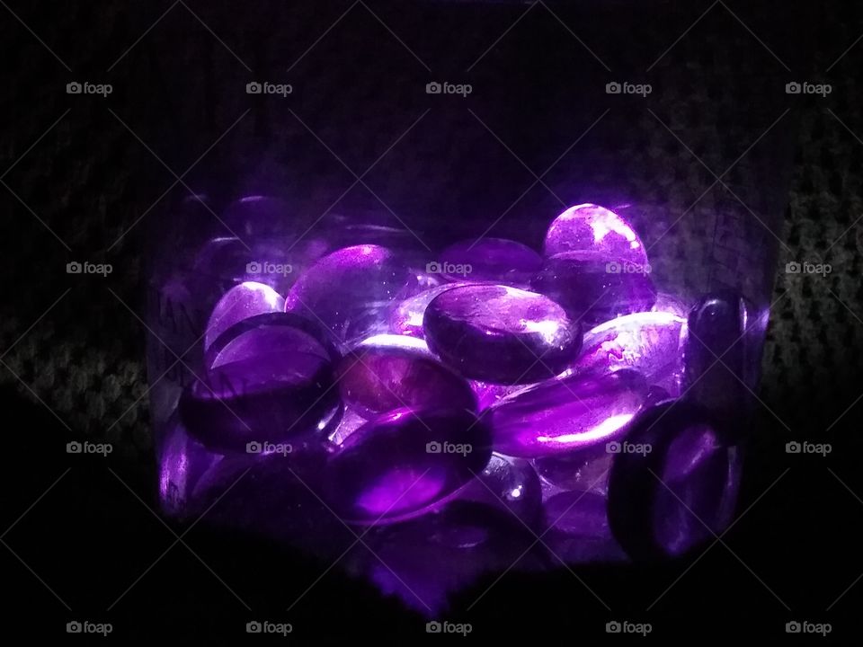 Glass pebbles in jar illuminated from below.