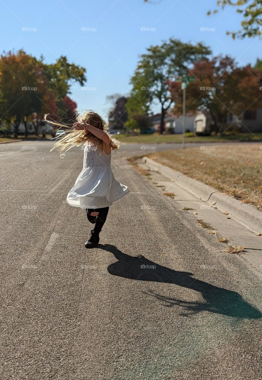 girl dancing in the street in the sunshine white dress with black boots twirling skirt and hair