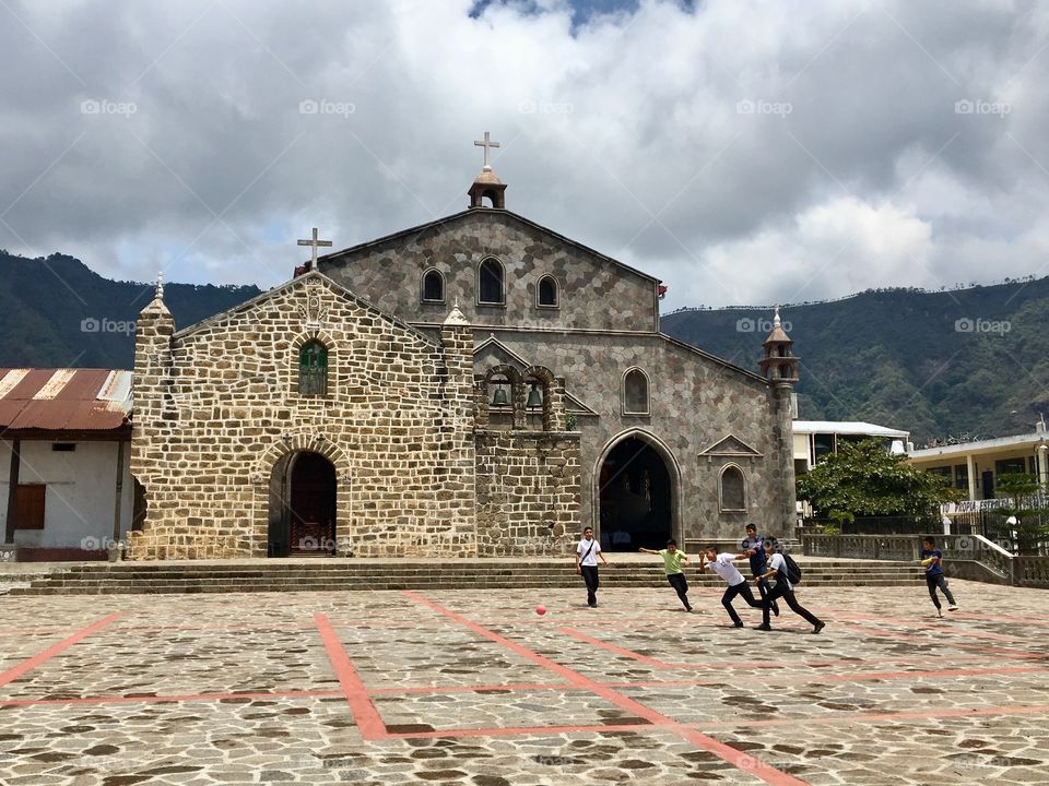 Young kids playing soccer in front of a church in a small Mayan town by Lake Atitlan, Guatemala 