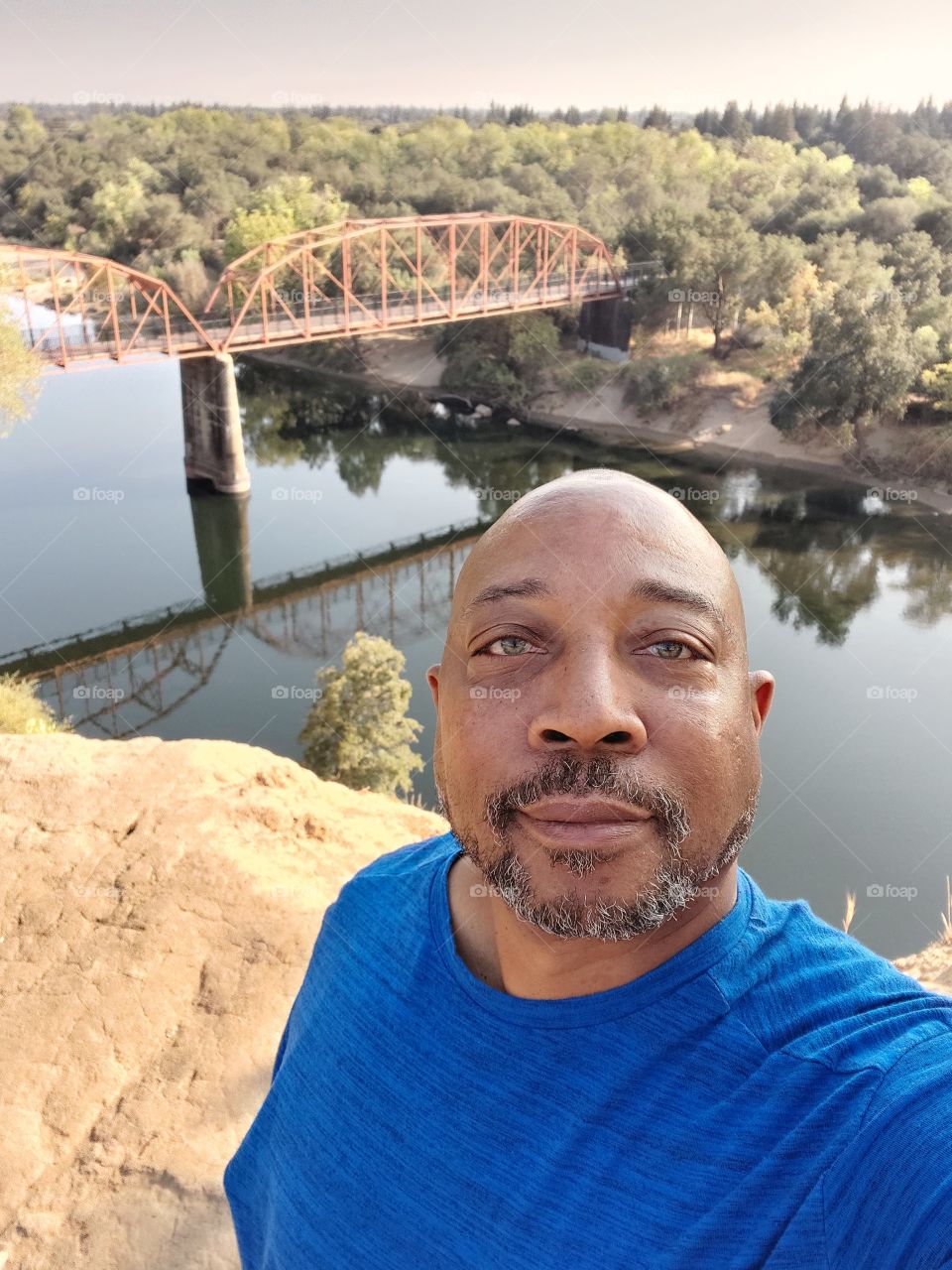 Selfie pic in nature with a foot bridge in the background