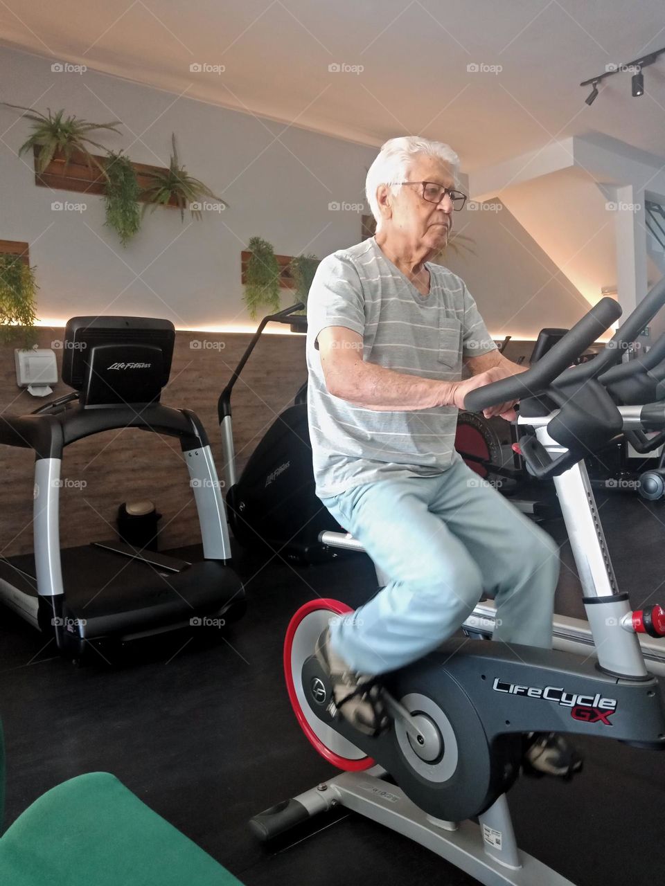 Elderly man on a bicycle in the gym