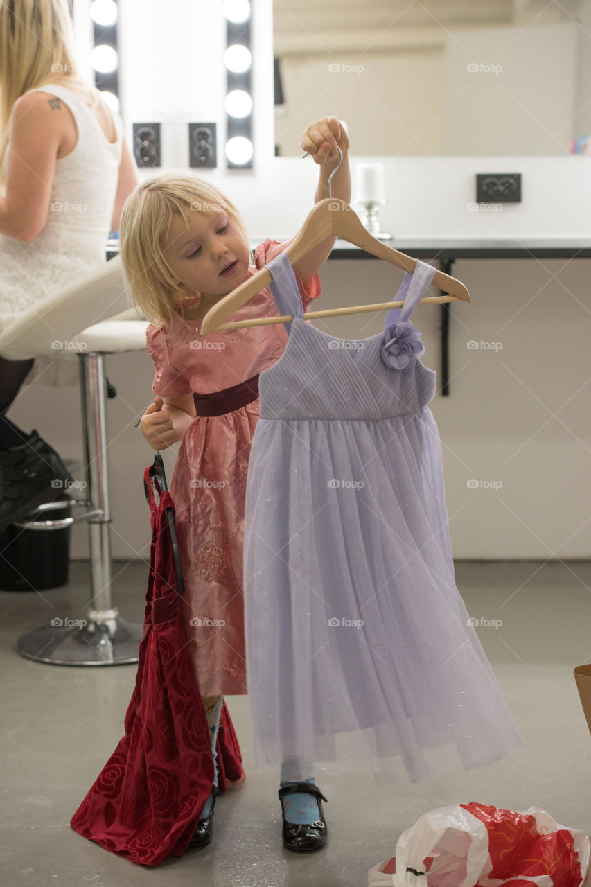 Four year old girl trying out dresses before a family photoshoot.